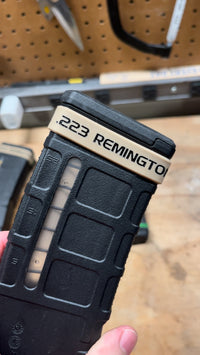 Thumbnail for Black rifle magazine with '223 Remington' text held by a hand against a blurred background